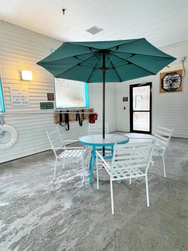 a table and chairs with a green umbrella in a room at AmericInn by Wyndham Petoskey in Petoskey
