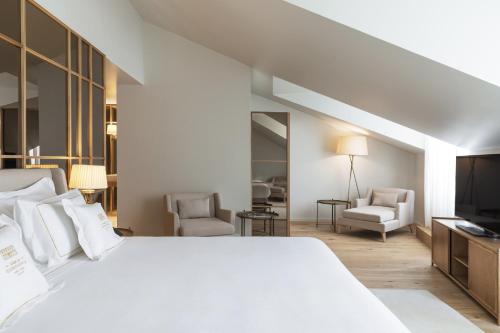 a white bedroom with a large bed and a tv at Casa da Companhia Hotel & Spa, Vignette Collection by IHG in Porto