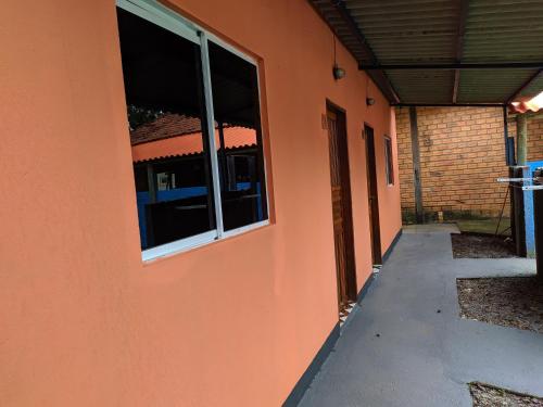 un edificio anaranjado con una ventana en el costado. en suítes Bomfass, en Alto Paraíso de Goiás