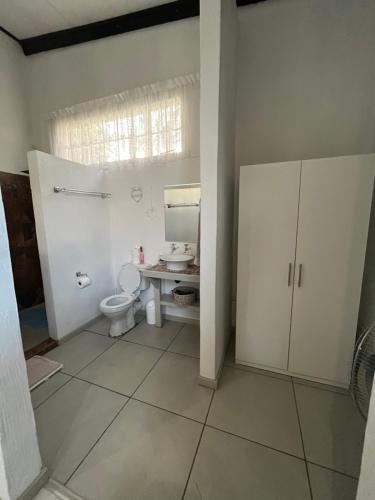 a bathroom with a toilet and a sink and a window at Le Soleil in Graskop