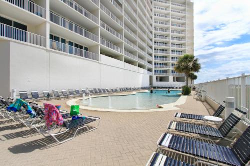 a group of lounge chairs next to a swimming pool at Lighthouse 714 in Gulf Shores