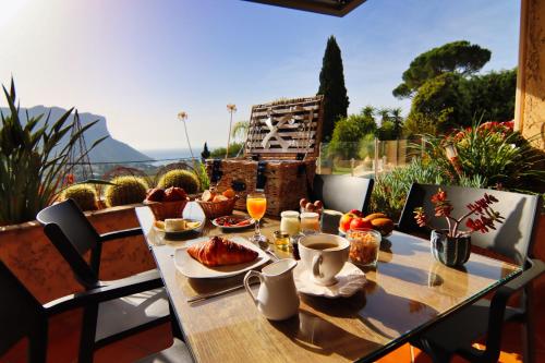 een tafel met eten en drinken op een balkon bij La Demeure Insoupçonnée in Cassis