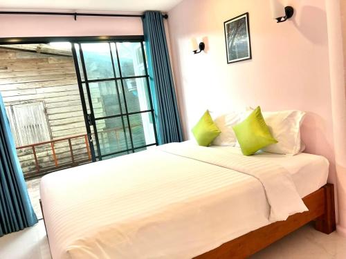 a bed in a room with a large window at Baan Purada in Ko Lanta