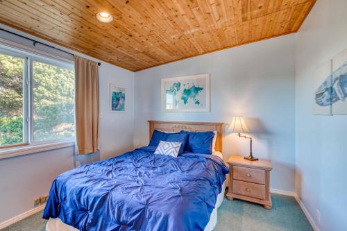 a bedroom with a blue bed and a window at The Salty Salmon - Meredith Lodging in Rockaway Beach