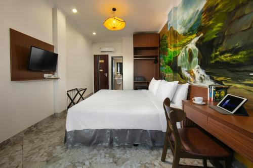 a hotel room with a bed and a desk and a tv at Hanoi La Cascada House & Travel in Hanoi