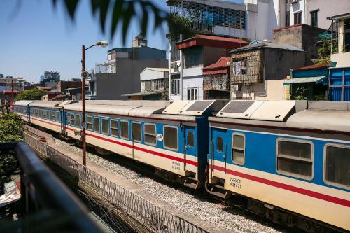 a train is sitting on the tracks next to buildings at Hanoi La Cascada House & Travel in Hanoi
