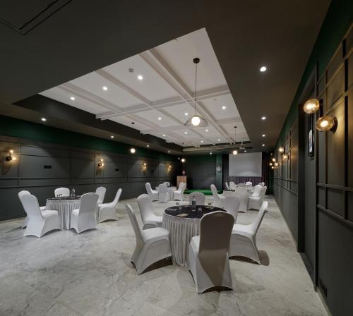 a restaurant with white tables and white chairs at Hotel Akruti, Nanded in Nānded