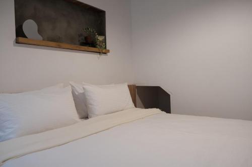 a white bed with white pillows in a room at 鹿耳宅宅 Lure Guesthouse in Tainan