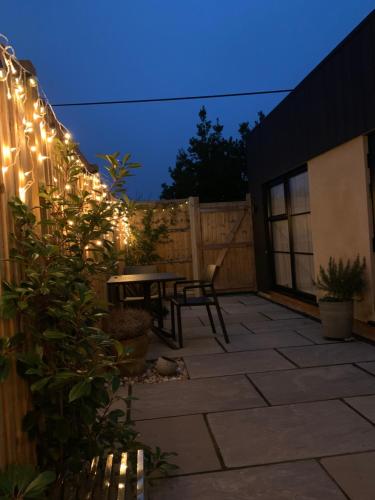 a patio with a table and lights on a fence at The Burrow at Tankerton in Whitstable