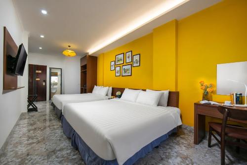 two beds in a hotel room with yellow walls at Hanoi La Cascada House & Travel in Hanoi
