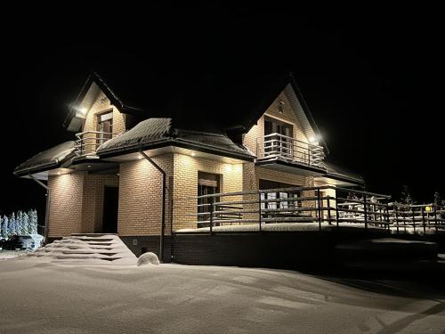 a house at night with snow in front of it at Domwigierski pl -Jeziorki -GR- Comfort-Ferienhaus-Polen - własna linia brzegowa i sauna in Wysoki Most