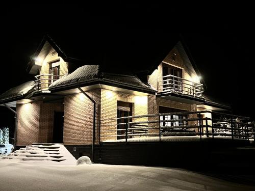 a house at night with snow in front of it at Domwigierski pl -Jeziorki -GR- Comfort-Ferienhaus-Polen - własna linia brzegowa i sauna in Wysoki Most