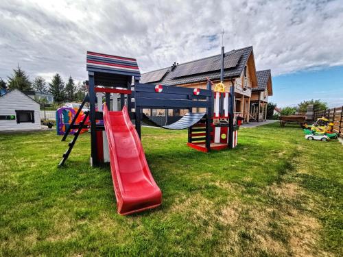 a playground with a slide in a yard at Czarne Domki Chłopy in Chłopy