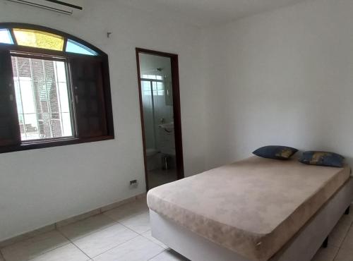 a bedroom with a bed and a window at Casa Perto da Praia Caraguatatuba in Caraguatatuba