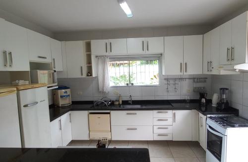 a kitchen with white cabinets and a window at Casa Perto da Praia Caraguatatuba in Caraguatatuba