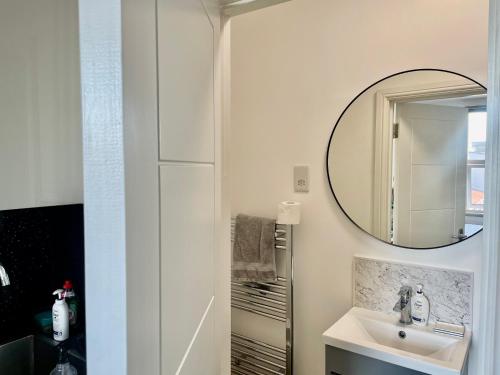 a bathroom with a sink and a mirror at Lovely self contained studio now available in London