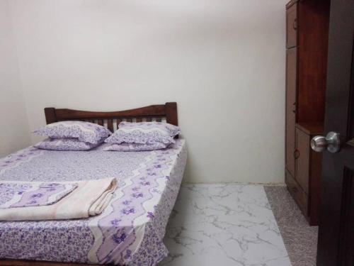 - une chambre avec un lit doté de draps et d'oreillers violets dans l'établissement Idaman guesthouse Malay only, à Kubang Semang