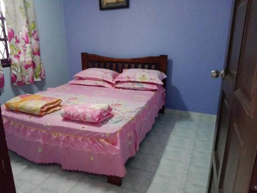 ein Schlafzimmer mit einem rosa Bett mit rosa Bettwäsche und Kissen in der Unterkunft Idaman guesthouse Malay only in Kubang Semang