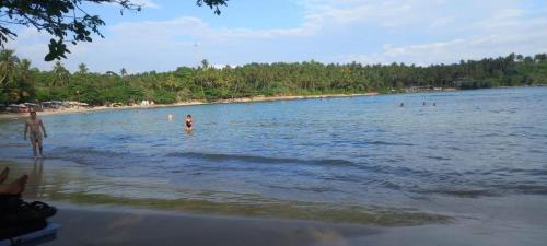 un grupo de personas en el agua en una playa en Surf Villa Hiriketiya en Matara