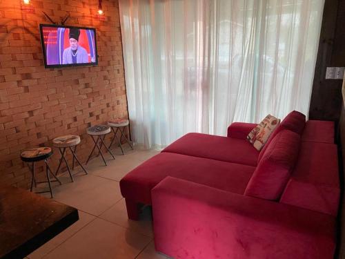 sala de estar con sofá rojo y TV en Casa Rio da Madre, en Palhoça