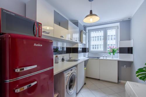 a kitchen with a red refrigerator and a washing machine at ClickTheFlat Żurawia Street Apart Rooms in Warsaw