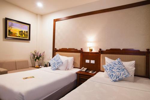 a hotel room with two beds and a couch at Western Hanoi Hotel in Hanoi