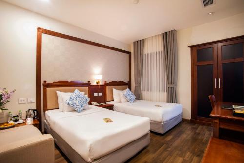 a hotel room with two beds and a desk at Western Hanoi Hotel in Hanoi