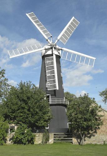 a windmill in a field with trees in front of it at The Windmill Hotel in Lincolnshire