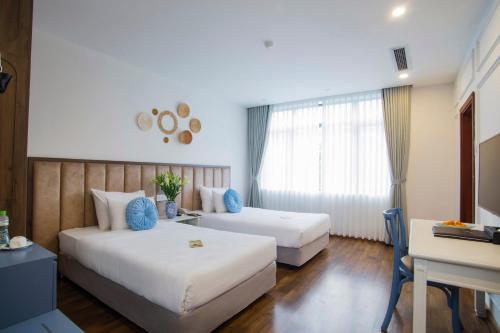 a hotel room with two beds and a desk at Western Hanoi Hotel in Hanoi