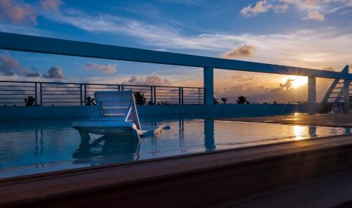 a chair sitting on the edge of a balcony with the sunset at Hotel DUCASSI SOL CARIBE in Punta Cana