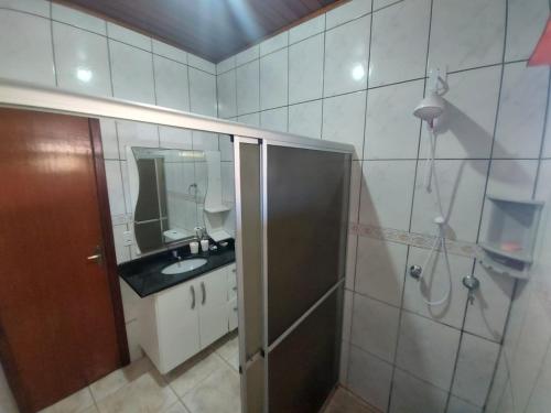 een badkamer met een douche, een wastafel en een spiegel bij Casa Barra da Ibiraquera in Imbituba