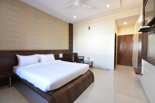 a bedroom with a large bed with white sheets at Hotel Sai Sparsh in Shirdi