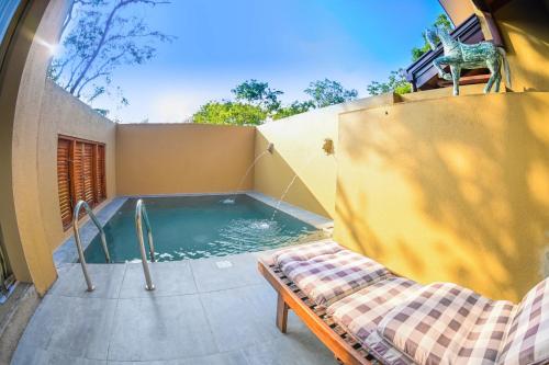 una piscina con un banco y una cama al lado en Allure Yala - Lakeside Luxury Suites, en Yala