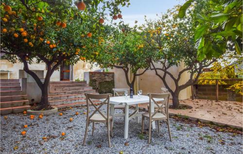 a white table and chairs under an orange tree at Gorgeous Home In Santa Lucia Del Mela in Santa Lucia del Mela