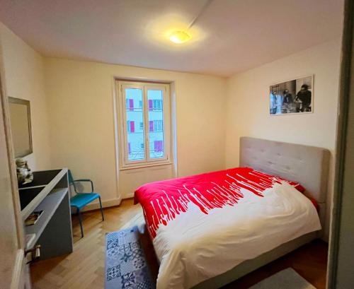 a bedroom with a bed with a red blanket on it at A deux pas du lac Leman ( Ouchy) joli appartement in Lausanne