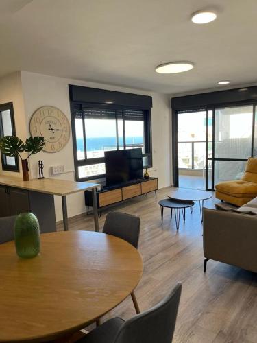 - un salon avec une table, des chaises et une télévision dans l'établissement Blue Sea Suite, à Ashkelon