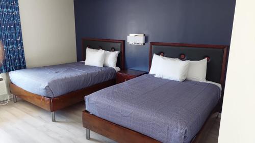 2 camas en una habitación de hotel con paredes azules en Economy 7 Inn Hampton, en Hampton