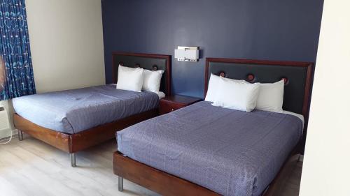 two beds in a hotel room with blue walls at Economy 7 Inn Hampton in Hampton
