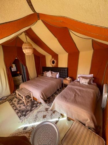 a large room with two beds in a tent at Erg Chebbi Sahara Camp in Merzouga