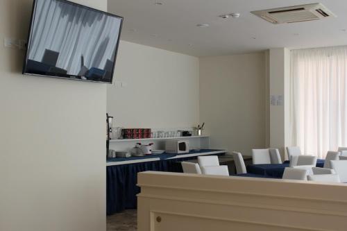 a waiting room with white chairs and a flat screen tv at Hotel Marina in Rimini