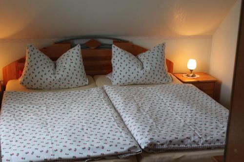 a bed with two pillows and a lamp on a table at Ferienwohnung-Roock in Oevenum