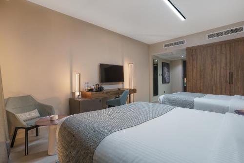 a hotel room with a bed and a desk and a tv at Hotel Holiday International in Sharjah