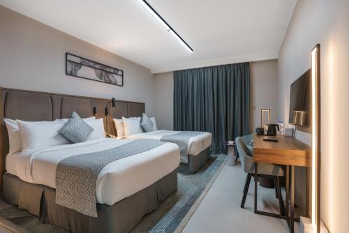 a hotel room with two beds and a desk at Hotel Holiday International in Sharjah
