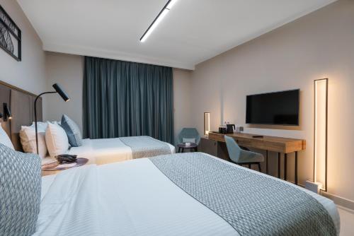 a hotel room with two beds and a desk and a television at Hotel Holiday International in Sharjah