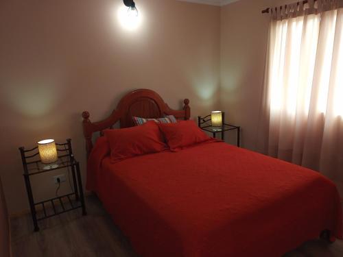 a bedroom with a red bed with two night stands at Departamento Arenas in Maipú