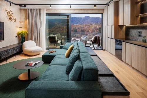 a living room with a green couch and a large window at Stejeris Nature-Inspired Luxury Apartment in Braşov