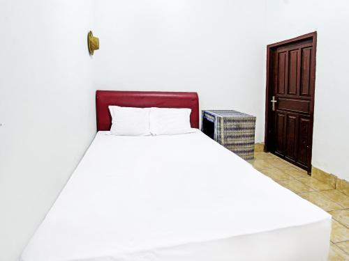 Cama blanca en habitación con puerta de madera en SPOT ON 91982 Dani Homestay en Narmada