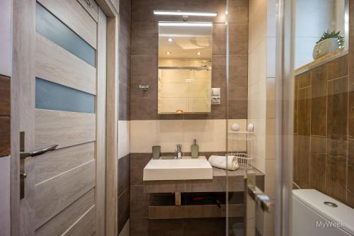 ein Bad mit einem Waschbecken und einem Spiegel in der Unterkunft Apartament Habel, MyWeek in Bystrzyca Kłodzka