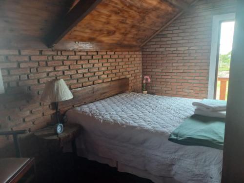 a bedroom with a brick wall and a bed at Ecovalle São Thomé in São Thomé das Letras