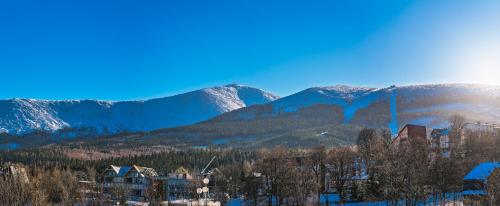 a building with mountains in the background with snow at Apartament w Cieplicach Panorama in Jelenia Góra